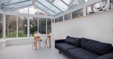 A white conservatory in Basingstoke with a navy sofa.