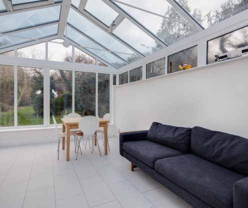 A white conservatory in Basingstoke with a navy sofa.