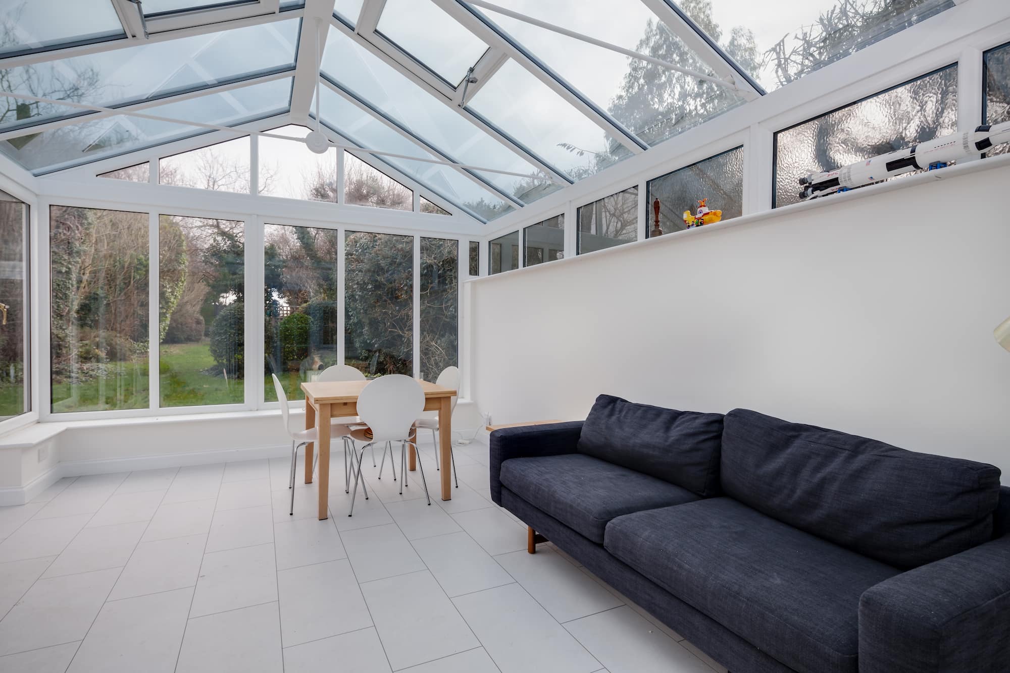 A white conservatory in Basingstoke with a navy sofa.