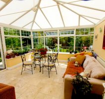 A conservatory in Basingstoke with sofas and tables and clear view of the garden.