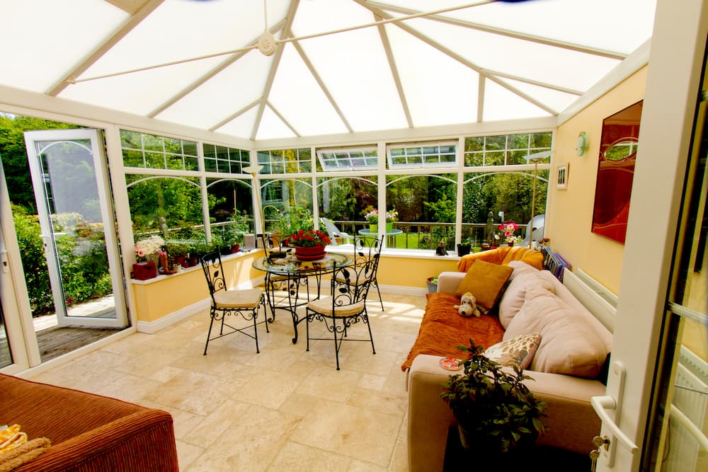 A conservatory in Basingstoke with sofas and tables and clear view of the garden.